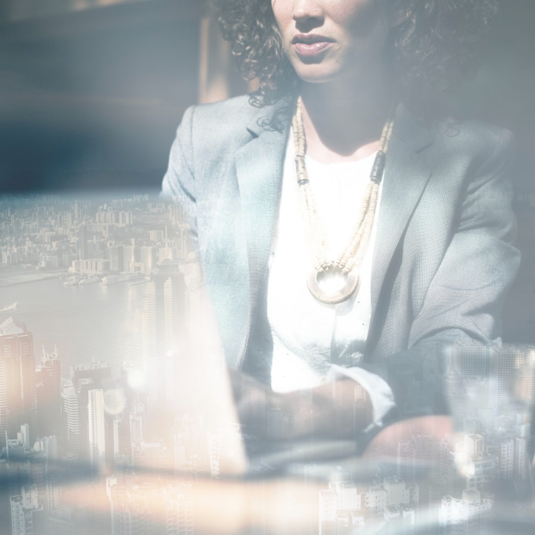 Geschäftsfrau, die an einem Laptop arbeitet mit Stadt als Hintergrund