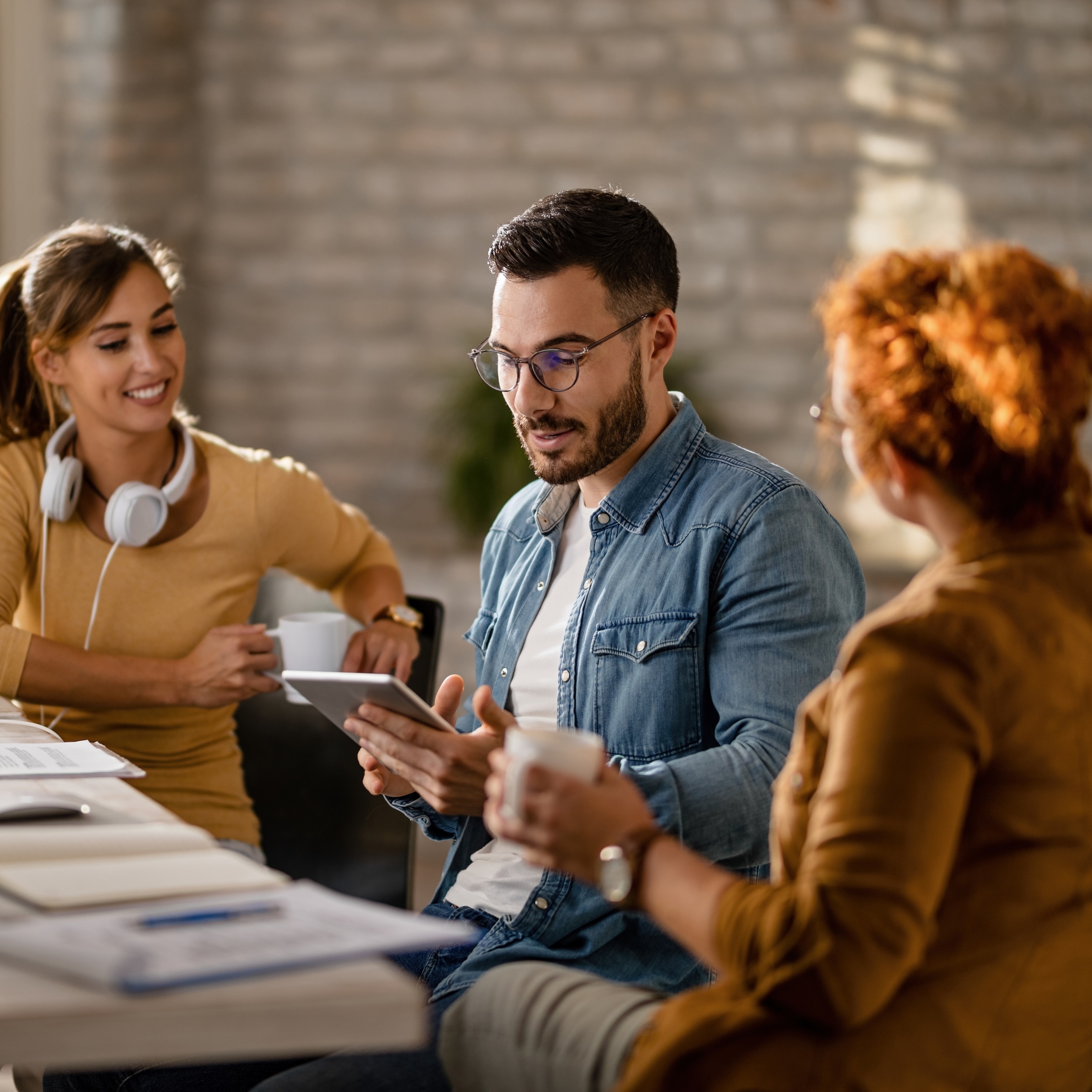 Team of young entrepreneurs having a business meeting in the office. Focus is on businessman using digital tablet.